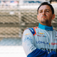 Stefan Wilson, dressed in his firesuit, stands in the pits of the Indianapolis Motor Speedway during practice for the 2022 Indy 500.